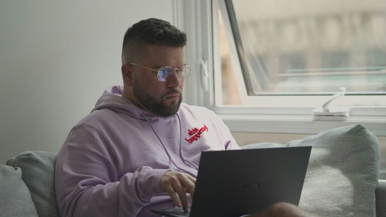 man in pink hoodie using macbook