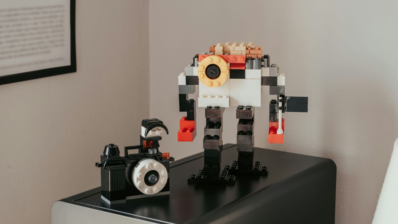 a lego robot sitting on top of a table next to a camera