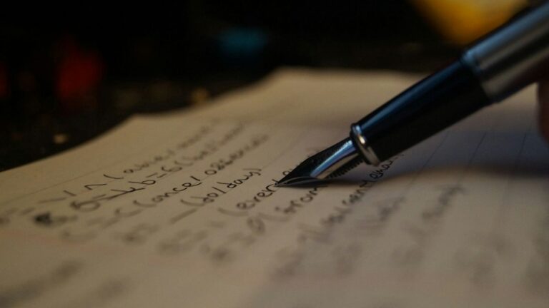 a person writing on a piece of paper with a pen